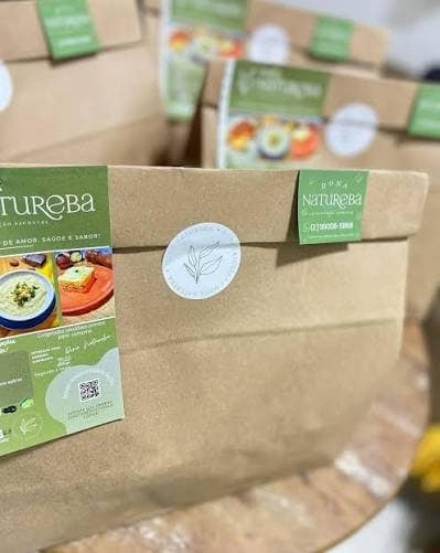 Sacolas kraft de delivery com adesivos e folheto da Dona Natureba